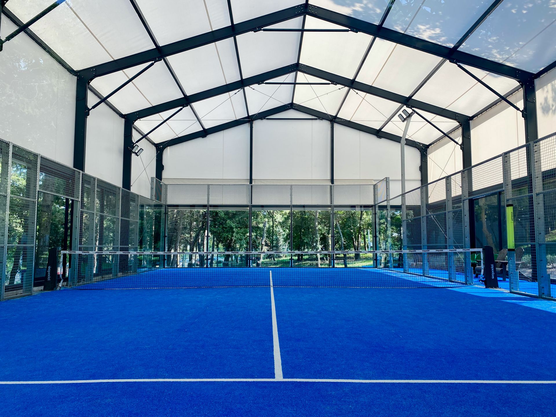 Pista de pádel indoor con superficie azul y estructura acristalada en Madrid