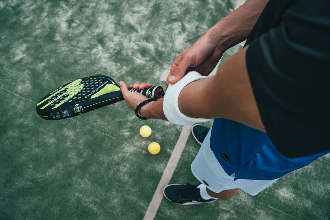 Jugador de pádel con muñequera blanca ajustando la pala Bullpadel en pista