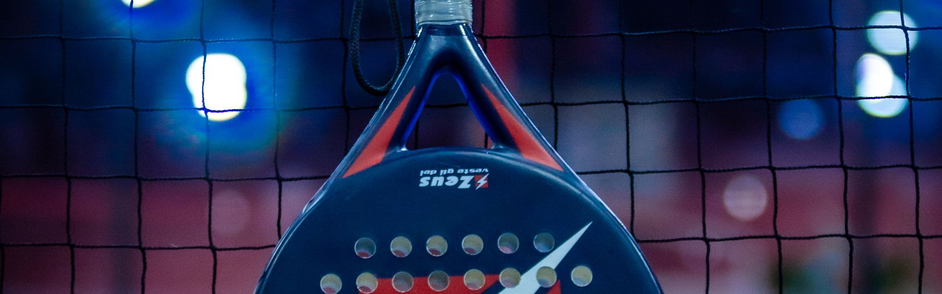 Pala de pádel y pelota sobre pista azul
