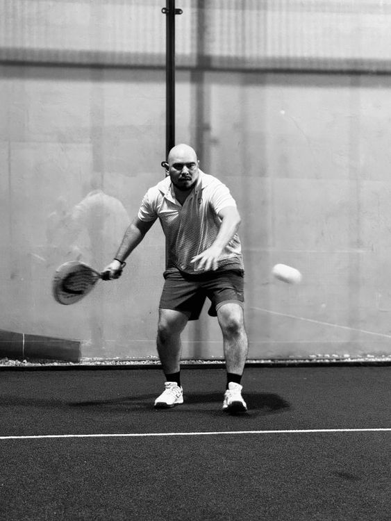 Jugador de pádel en acción dentro de pista cubierta