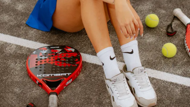 Zapatillas de pádel de mujer junto a una pala roja